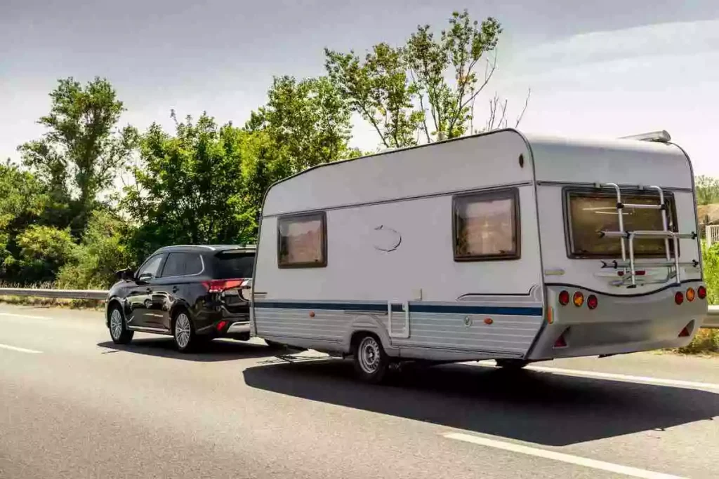 BMW SUV towing a Caravan trailer on a freeway road.